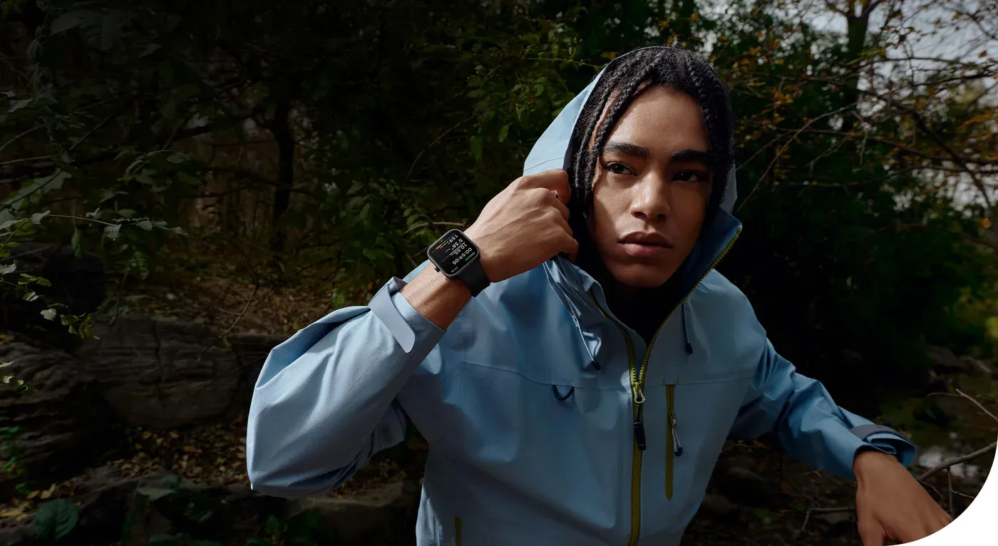 Une coureuse en veste de pluie, la Redmi Watch 5 au poignet, dans un sous-bois